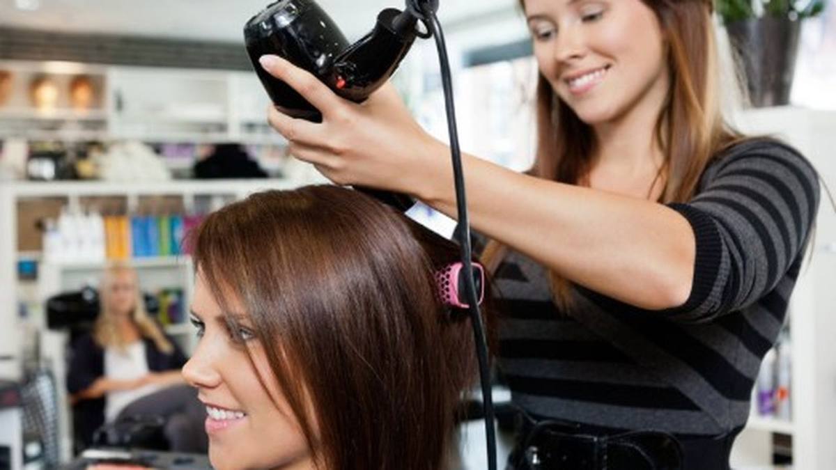 Indian salon owner using HisaabNow salon POS billing app on his phone during morning rush — Delhi salon, stylists arriving, first clients walking in